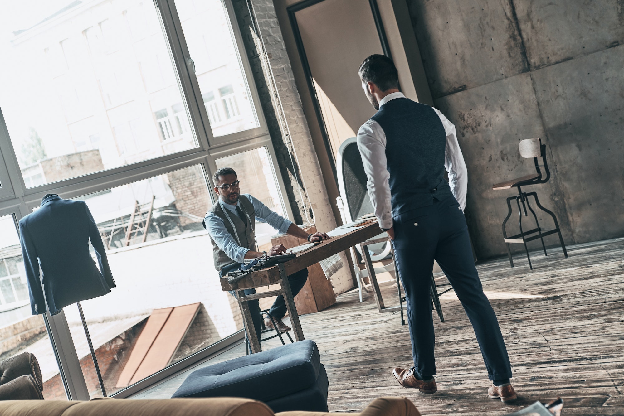 Perfect men. Two young fashionable men looking at each other while working in workshop